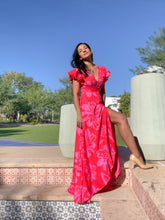 Woman in a red dress standing outdoors with trees and clear sky in the background