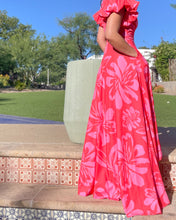 Person wearing a pink floral dress sitting on a stone bench outdoors.