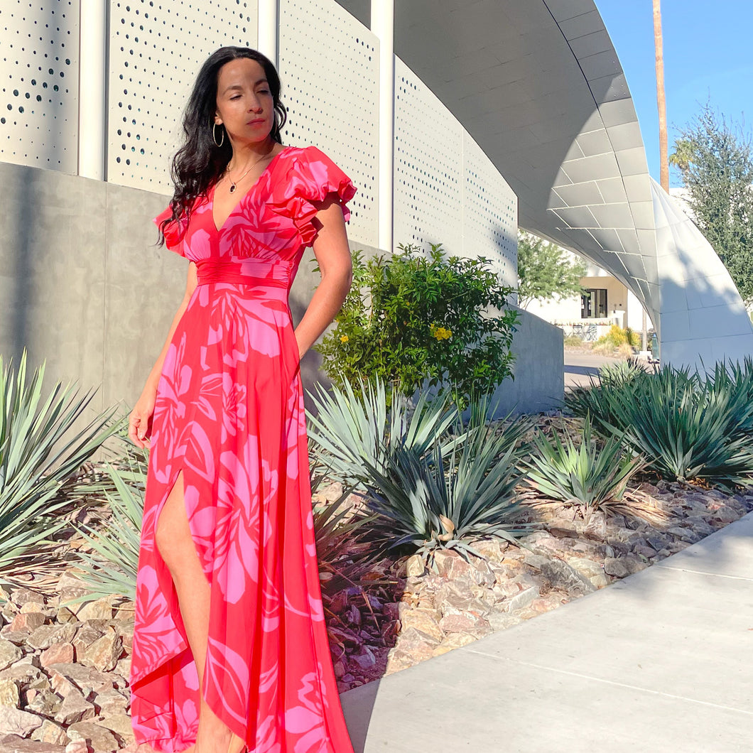 Woman in a red dress standing in front of a modern building with palm trees in the background