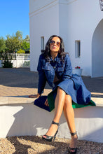 Woman in a indigo set sitting on a white building's ledge.