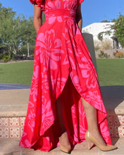 Person wearing a bright red floral dress with beige shoes outdoors.